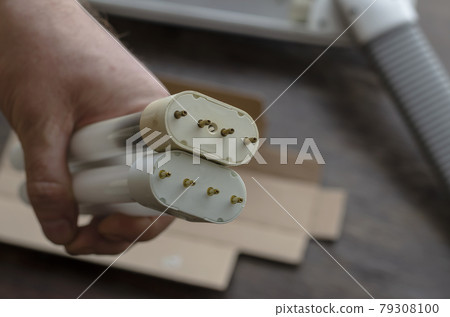 Adult Man's hand holds a burned-out and a new compact fluorescent bulb. 79308100