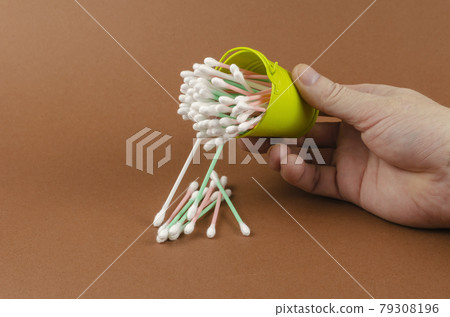 Small bucket, cotton swabs and a hand on a brown background. Small bucket, cotton swabs and a hand on a brown background. 79308196
