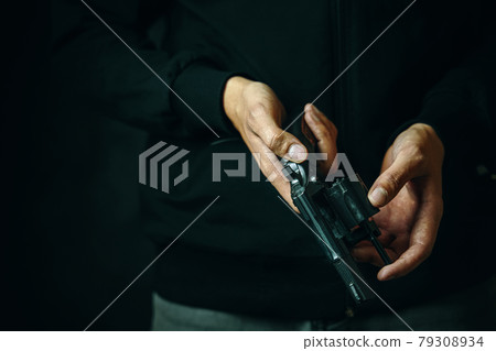 Close up of man reloading revolver. 79308934