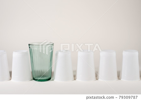 Glass and many plastic cups in a raw. Glass or plastic. Reusable versus disposable. 79309787