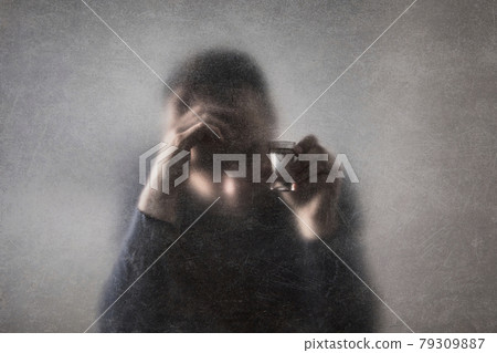 Man with a glass of vodka behind a dusty scratched glass. Alcoholism concept. Man with a glass of vodka behind a dusty scratched glass. Alcoholism concept. 79309887