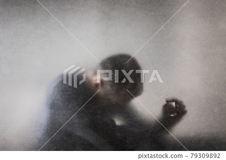 Man with a glass of vodka behind a dusty scratched glass. Alcoholism concept. Man with a glass of vodka behind a dusty scratched glass. Alcoholism concept. 79309892