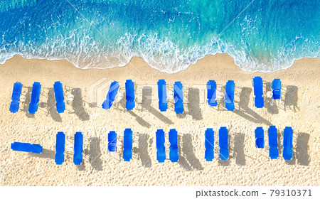 Empty blue sun beds on yellow sand beach, aerial panorama from directly above 79310371