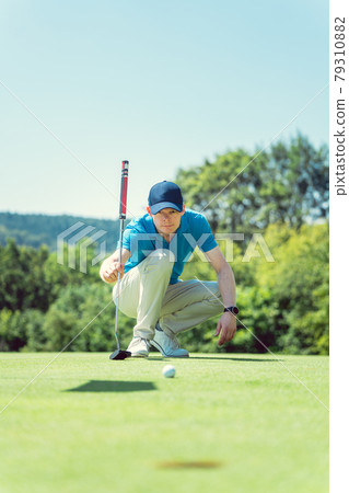 Golf player taking measure to hole in on the green Golf player taking measure to hole in on the green 79310882