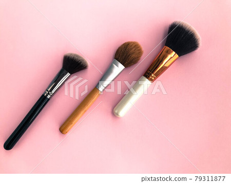 three tassels on a pink matte background. brushes for blush, powder, foundation and dry textures for contouring. face makeup. personal care, beauty and fashion 79311877
