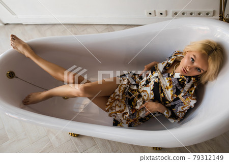 Blonde woman in dress in empty bath. 79312149