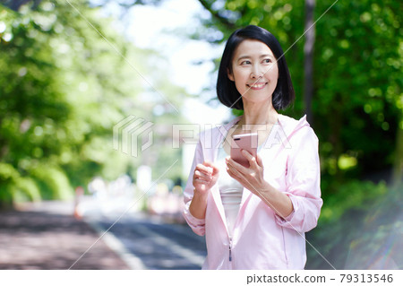 中年婦女穿著新鮮綠色的運動服並使用智能手機 79313546