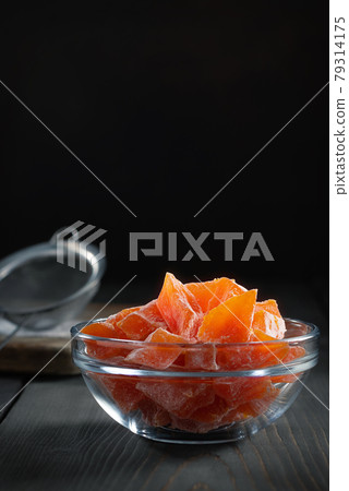 Natural farm homemade candied pumpkin fruits sprinkled with powdered sugar in a glass bowl on a wooden table 79314175