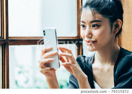 A young woman looking at a smartphone at home A young woman looking at a smartphone at home 79315872
