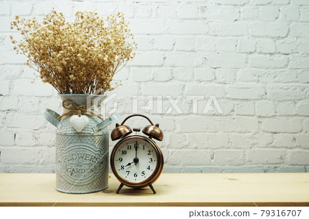 Dried flower in metal vase and alarm clock with space copy on white brick wall background 79316707