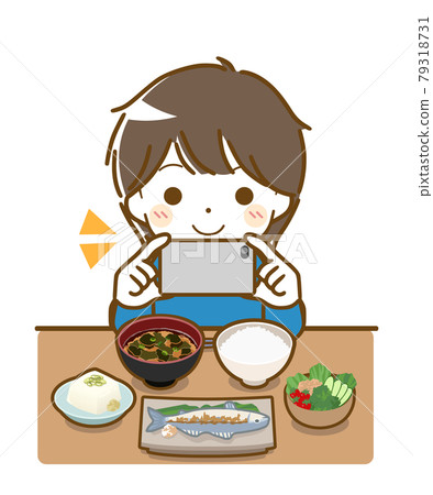 一個小男孩一邊吃飯一邊用智能手機拍照 79318731