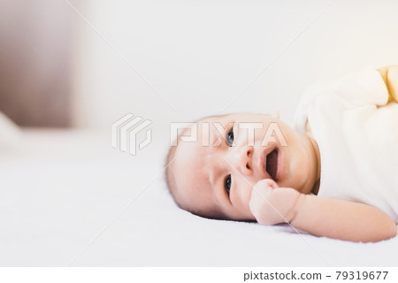 Crying little asian newborn baby lying on a comfortable bed Crying little asian newborn baby lying on a comfortable bed 79319677