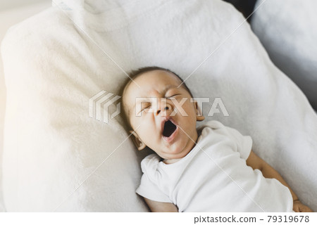 Lazy newborn baby yawning before sleep on a comfortable bed at home Lazy newborn baby yawning before sleep on a comfortable bed at home 79319678