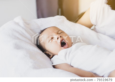 Sweet newborn baby yawning before sleep on a comfortable bed at home 79319679