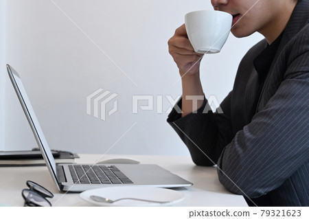 Cropped shot businessman drinking coffee and reading email on laptop computer. 79321623