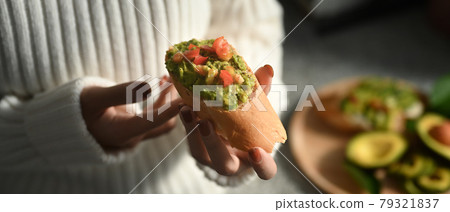 Cropped shot woman holding avocado sandwiches. Cropped shot woman holding avocado sandwiches. 79321837