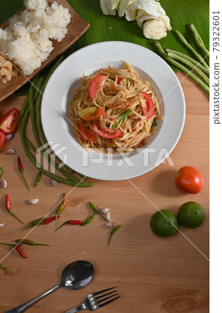 Spicy green papaya salad in white plate on wooden table. 79322601