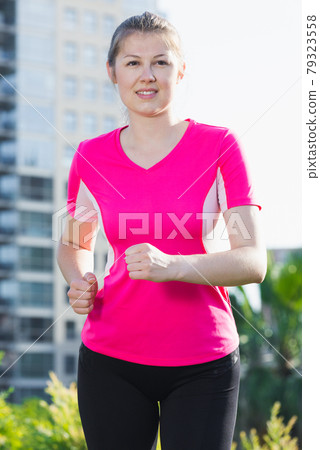 Female in pink T-shirt is jogging 79323558