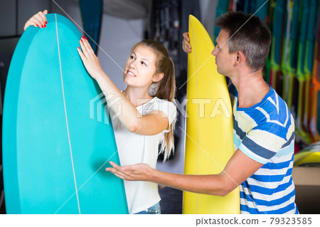 couple is demonstraiting surfboard in nautical shop. couple is demonstraiting surfboard in nautical shop. 79323585