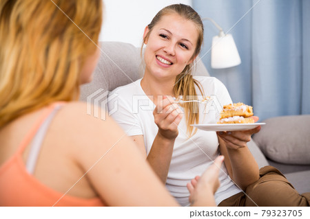 women on the sofa with plate of cake 79323705