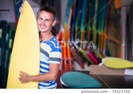 male is posing with surfboard in store on the beach. male is posing with surfboard in store on the beach. 79323708