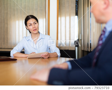Business man and woman in office filling up documents Business man and woman in office filling up documents 79323710