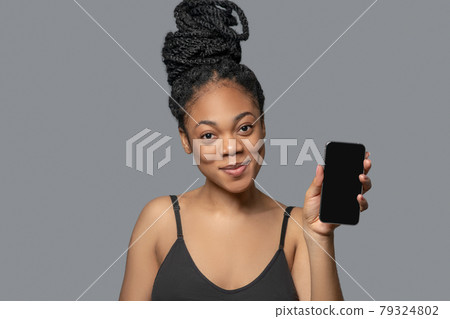 Woman with hair bun in black clothes holding a smartphone 79324802