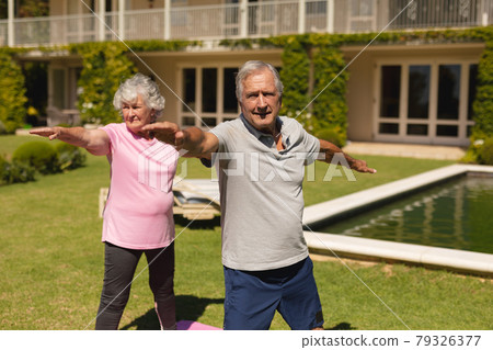 Senior caucasian couple practicing yoga, stretching in sunny garden Senior caucasian couple practicing yoga, stretching in sunny garden 79326377