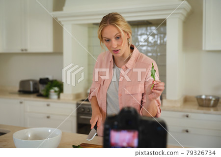 Caucasian woman in kitchen preparing food, holding salad leaf to camera, making cooking vlog Caucasian woman in kitchen preparing food, holding salad leaf to camera, making cooking vlog 79326734
