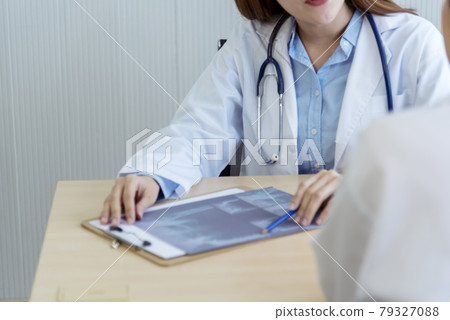 Two asian women doctors discuss meeting doctor's office medical clinic looking x-ray film consulting patient disease. Asian medical lab young women talking together discussing healthcare teamwork Two asian women doctors discuss meeting doctor's office medical clinic looking x-ray film consulting patient disease. Asian medical lab young women talking together discussing healthcare teamwork 79327088