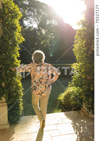Senior caucasian woman leaning on column in sunny garden Senior caucasian woman leaning on column in sunny garden 79327177