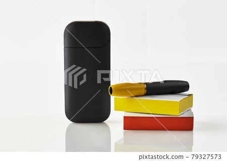 New generation black electronic cigarette is on red and yellow matchboxes, battery, isolated on white. Heating tobacco system. Advertising, close up New generation black electronic cigarette is on red and yellow matchboxes, battery, isolated on white. Heating tobacco system. Advertising, close up 79327573