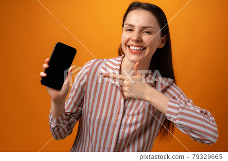 Happy smiling young woman showing you black smartphone screen with copy space Happy smiling young woman showing you black smartphone screen with copy space 79329665