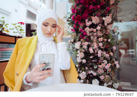 Young muslim woman in hijab using her smartphone in cafe 79329697