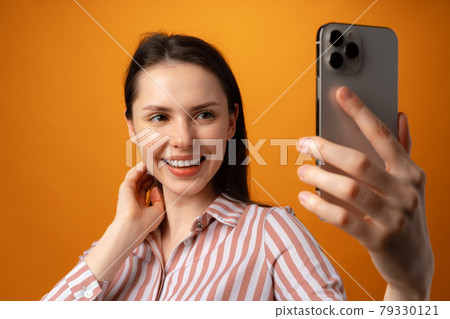 Portrait of young attractive woman using her smartphone against yellow background 79330121