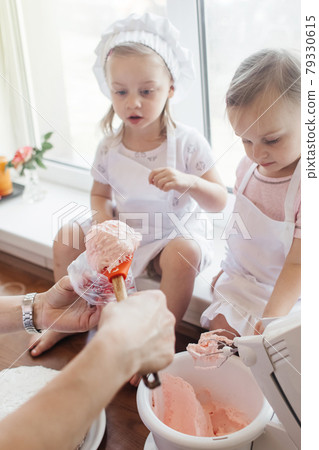 Children in the kitchen cook with their parents. Making homemade cake, pastries or cookies for the whole family. Happy childhood concept. Little twin sisters in kitchen aprons and chef hats Children in the kitchen cook with their parents. Making homemade cake, pastries or cookies for the whole family. Happy childhood concept. Little twin sisters in kitchen aprons and chef hats 79330615