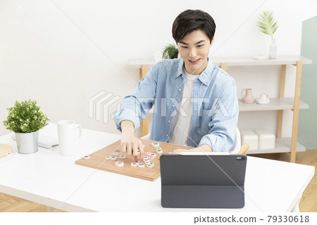 Asian young man learning chess through online class using tablet device Asian young man learning chess through online class using tablet device 79330618
