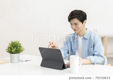 Asian young man using tablet device and digital pen Asian young man using tablet device and digital pen 79330633