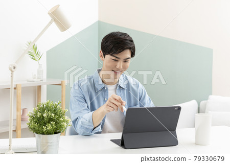 Asian young man using tablet device and digital pen Asian young man using tablet device and digital pen 79330679