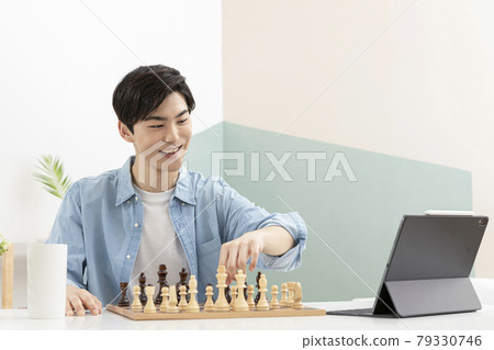 Asian young man learning chess through online class using tablet device Asian young man learning chess through online class using tablet device 79330746