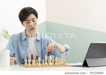 Asian young man learning chess through online class using tablet device Asian young man learning chess through online class using tablet device 79330900