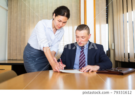 Business man and woman in office filling up documents Business man and woman in office filling up documents 79331612
