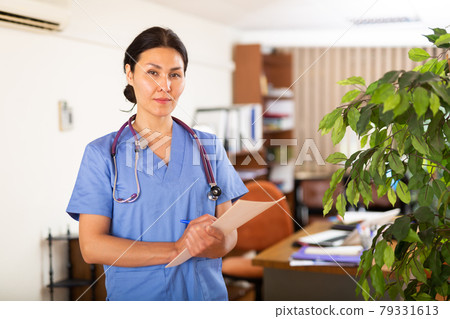 Polite Asian female doctor with clipboard meeting in clinic Polite Asian female doctor with clipboard meeting in clinic 79331613
