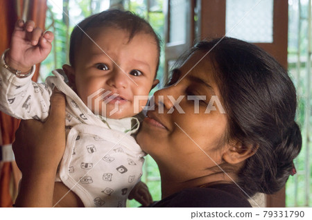 Happy Baby Loves mom Kisses. Loving Mother kissing cute little adorable kid on her lap. Close-up portrait. Indian ethnicity. Front view. Happy parents day Motherhood parenthood togetherness background Happy Baby Loves mom Kisses. Loving Mother kissing cute little adorable kid on her lap. Close-up portrait. Indian ethnicity. Front view. Happy parents day Motherhood parenthood togetherness background 79331790