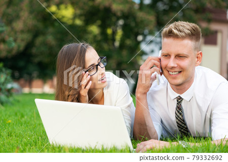 businessman and businesswoman with a laptop in a city park 79332692