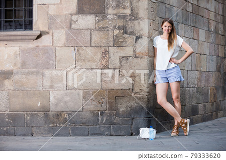 Young woman standing on stone wall background Young woman standing on stone wall background 79333620