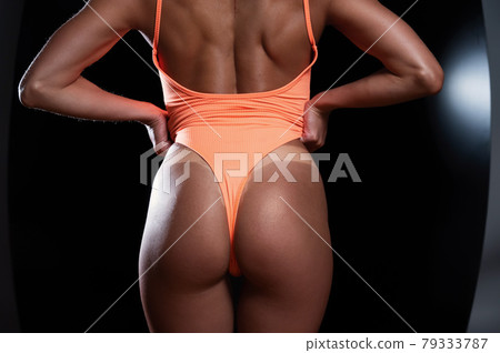 A faceless woman in an orange swimsuit demonstrates the result of an instant tan A faceless woman in an orange swimsuit demonstrates the result of an instant tan 79333787