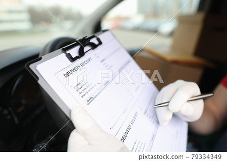 Gloved courier filling out delivery receipt using ballpoint pen closeup Gloved courier filling out delivery receipt using ballpoint pen closeup 79334349