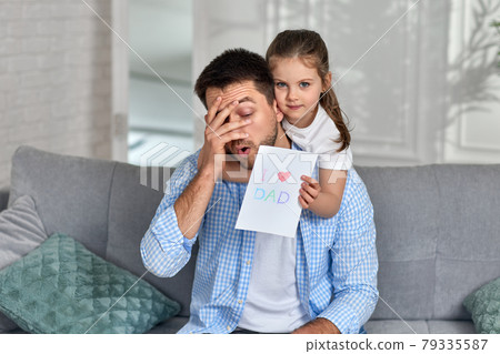 daughter congratulates her father and gives him postcard. 79335587