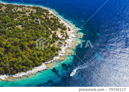 Lighthouse of Fiskardo village. Yacht boat in blue sea arrive in the port in Kefalonia island, Greece 79336117
